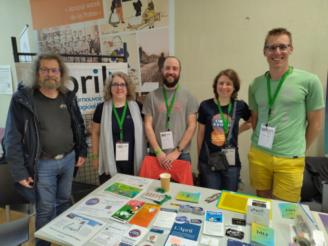 5 personnes
debout derrière la table d'un stand, sur laquelle il y a de nombreux documents